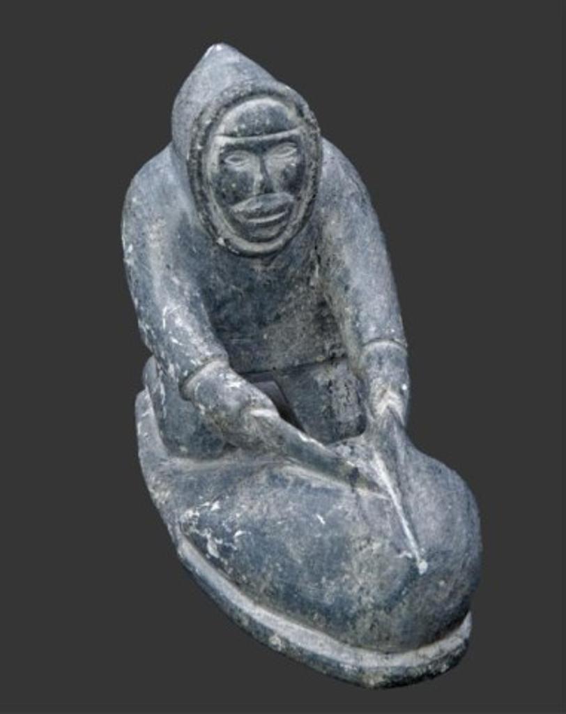 Levi Panipak (1961) - A grey stone carving of a hunter flensing a seal