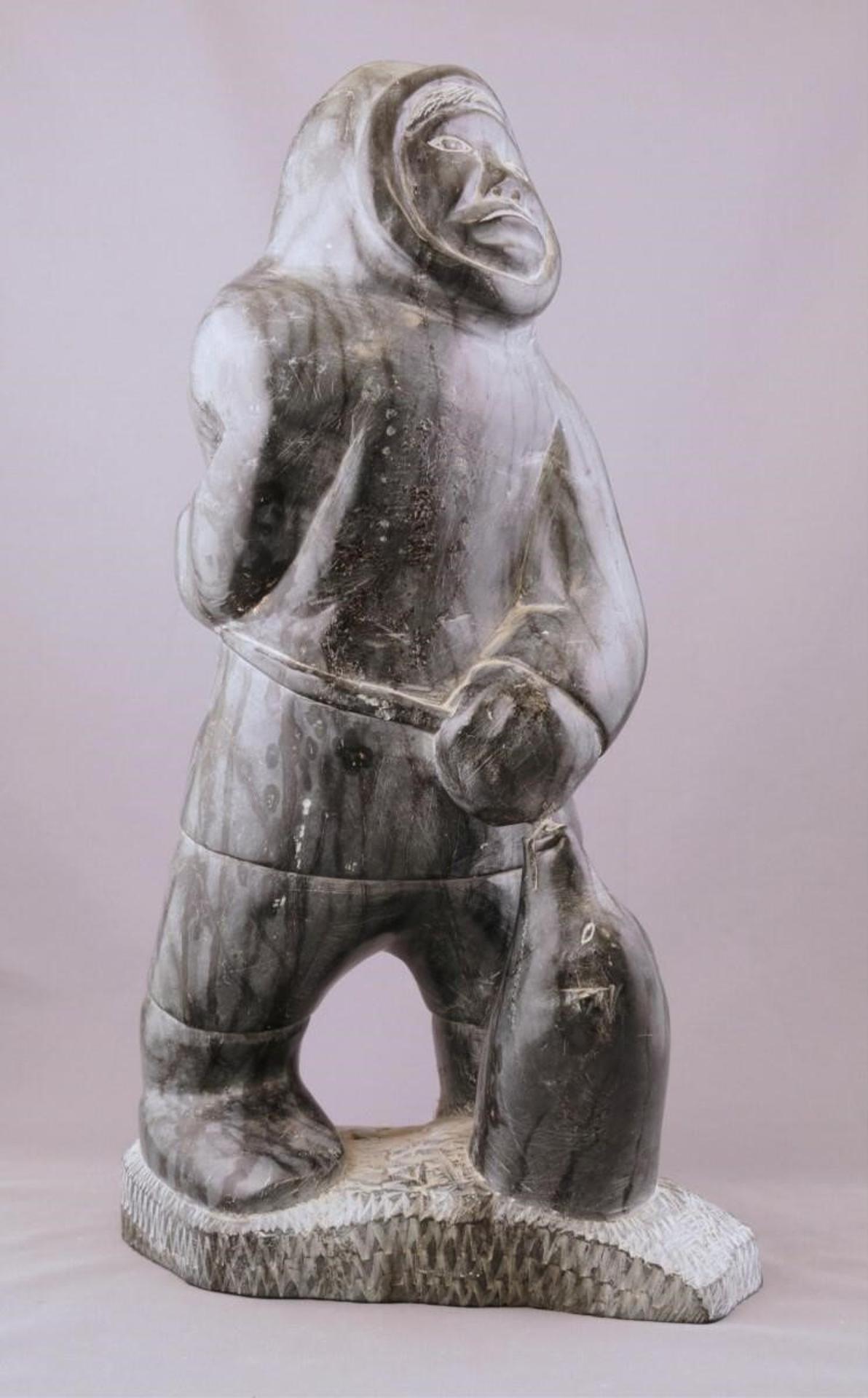 Noah Nowrakudluk (1916) - a grey-black stone carving of a Hunter Pulling a Seal out of the Ice