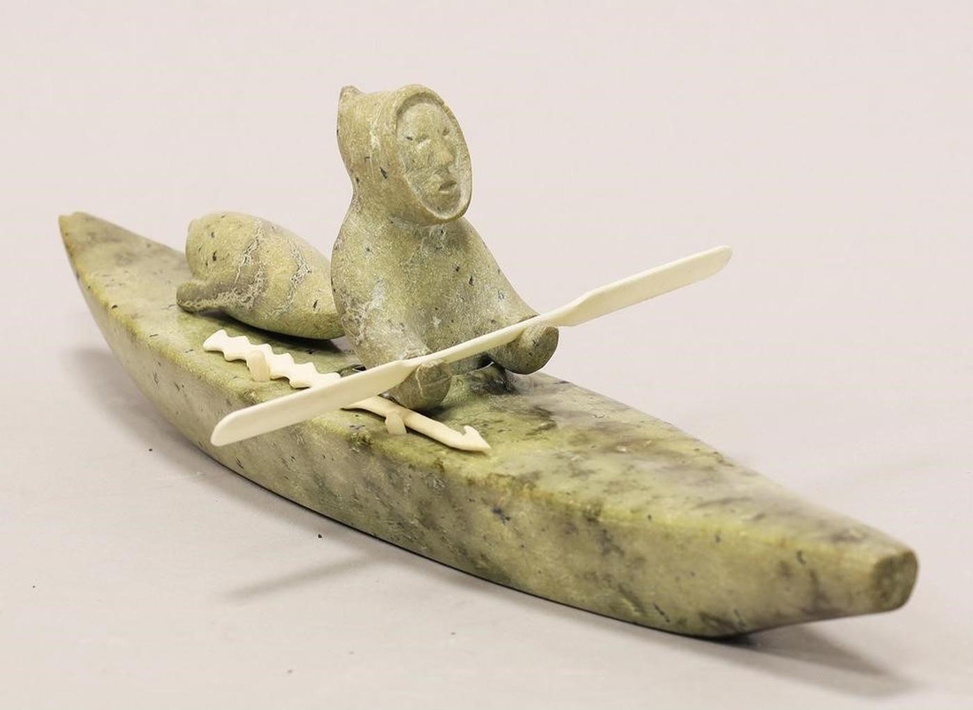 Peter Arnatsiaq (1928) - A light green stone carving of a Hunter with Seal in a Kayak