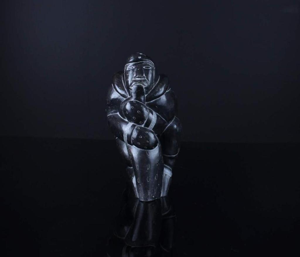 Peter Anautak Akulivik - a black stone carving of a hunter holding a seal
