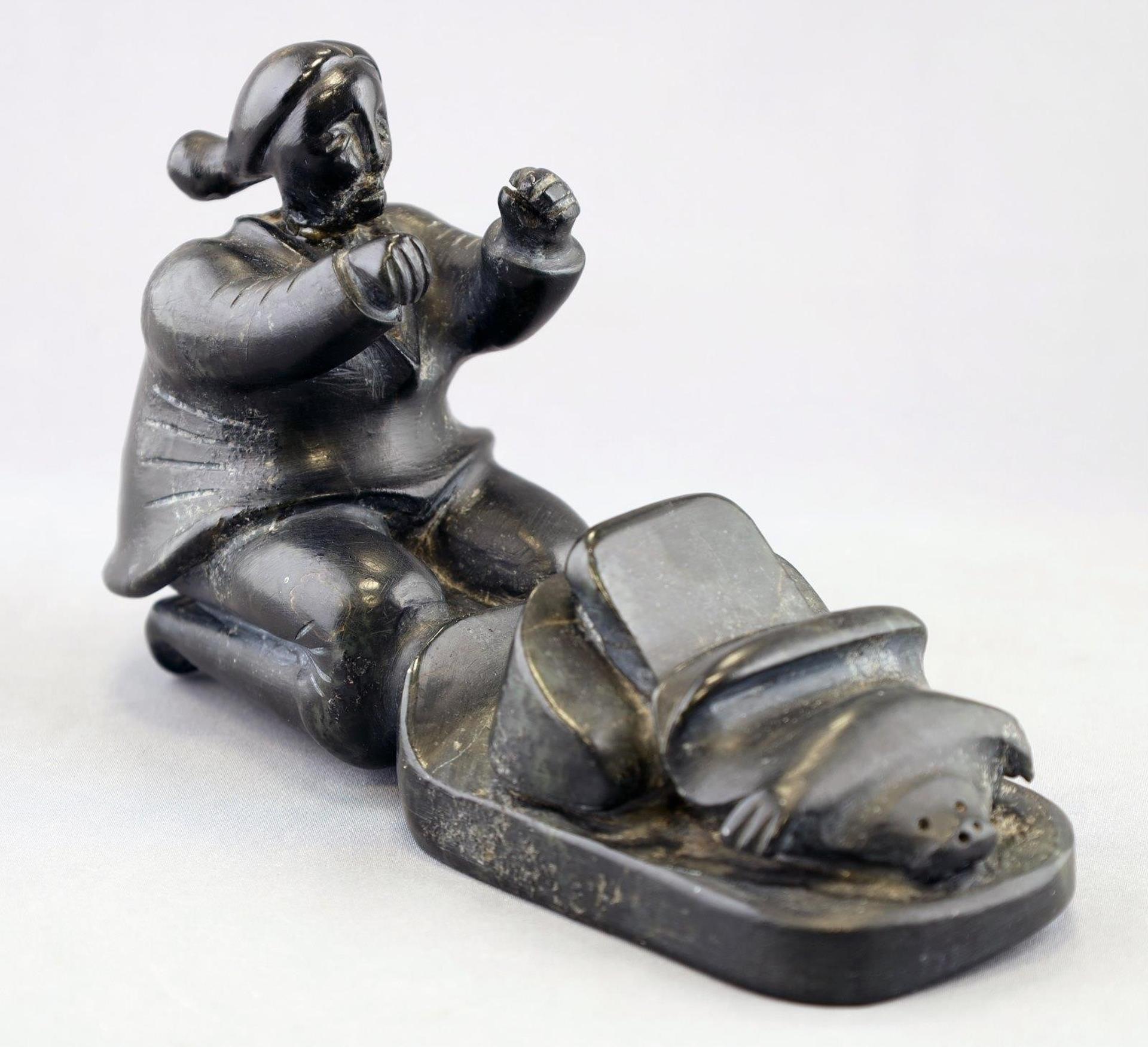 Henry Napartuk (1932-1985) - a black stone carving of a Kneeling Woman Skinning a Seal